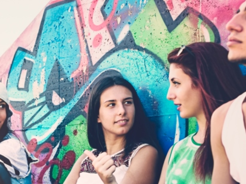 5 teenagers sitting at a wall