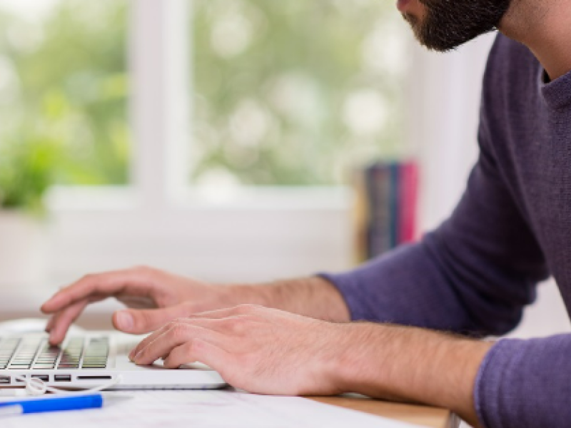 Man typing on laptop keyboard