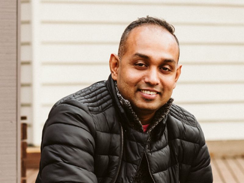smiling man sitting on an outdoor deck
