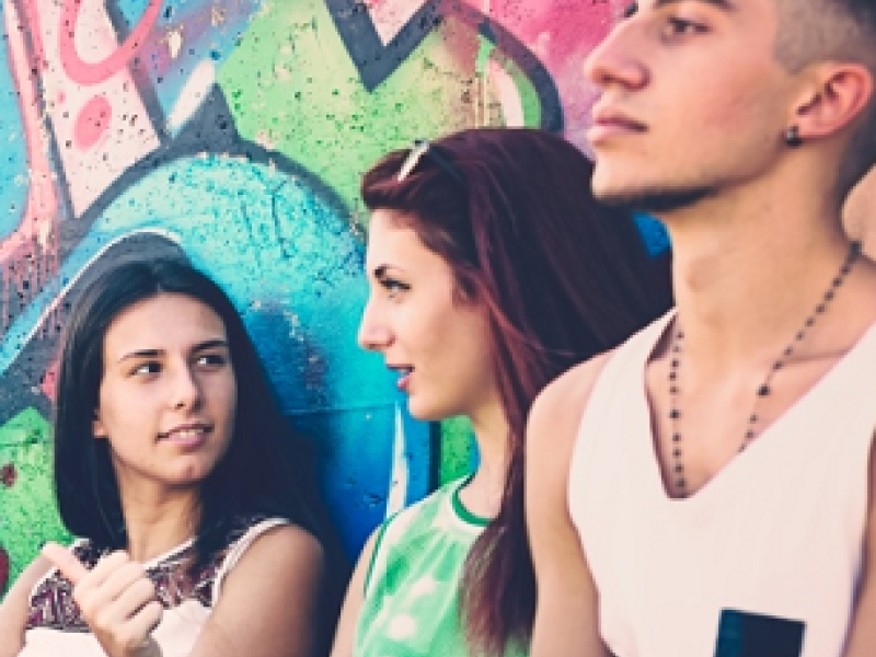 Three older children sitting against a wall. Two girls and one boy.