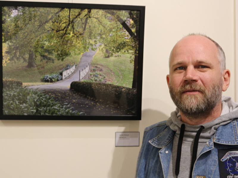 Dorian standing with artwork of trails and parkland.