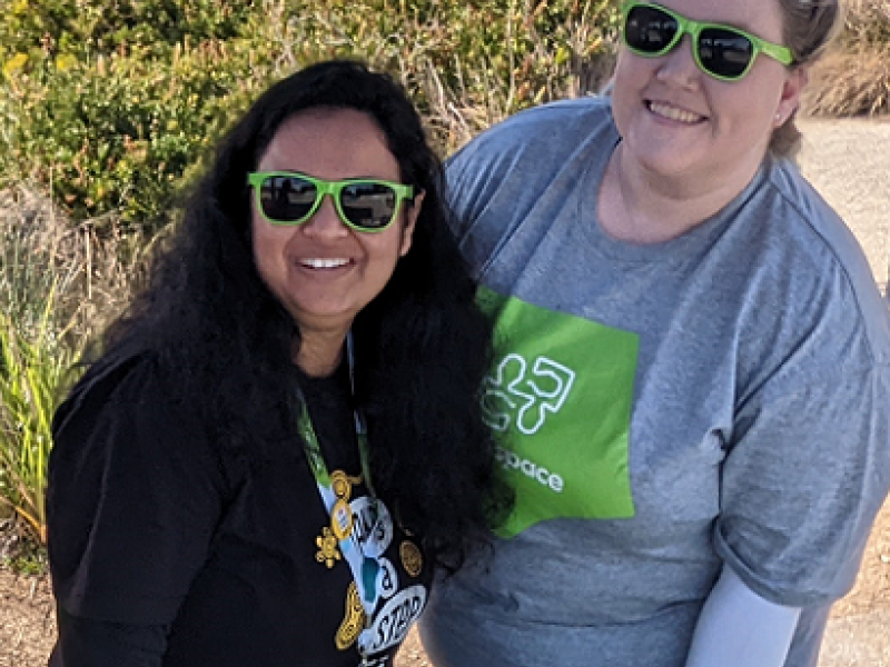 two woman smiling and wearing green sunglasses 
