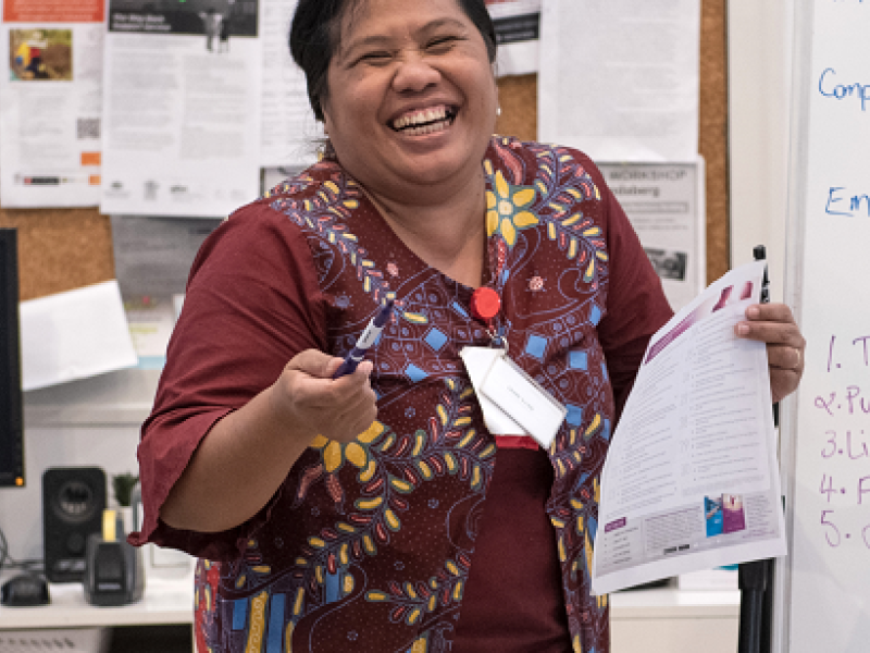 woman laughing and making a presentation to a group of people