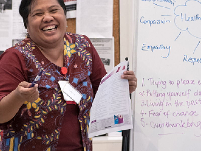 Woman holding paper and facilitating class. Big smile.