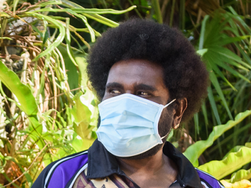 man wearing a face mask talking to another man