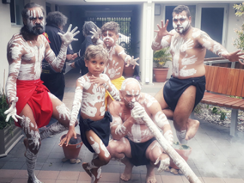 Three men and two boy's, Aboriginal and Torres Strait Islander, dancing and playing music