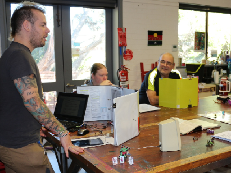 Man standing speaking to people sitting around a table