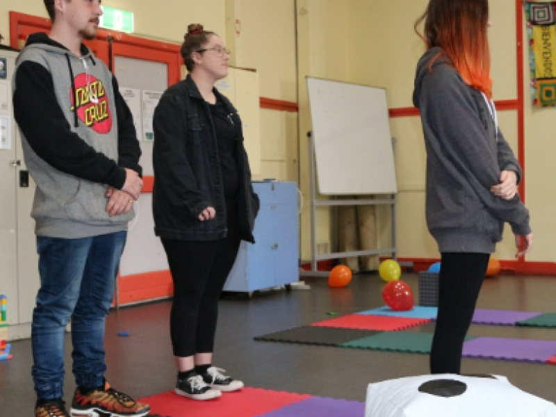 Three people standing on a giant board game