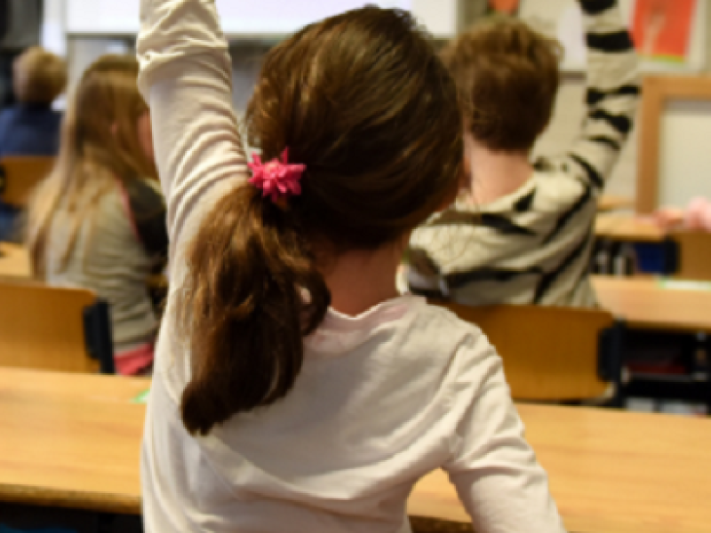 girl in a classroom raising her hand