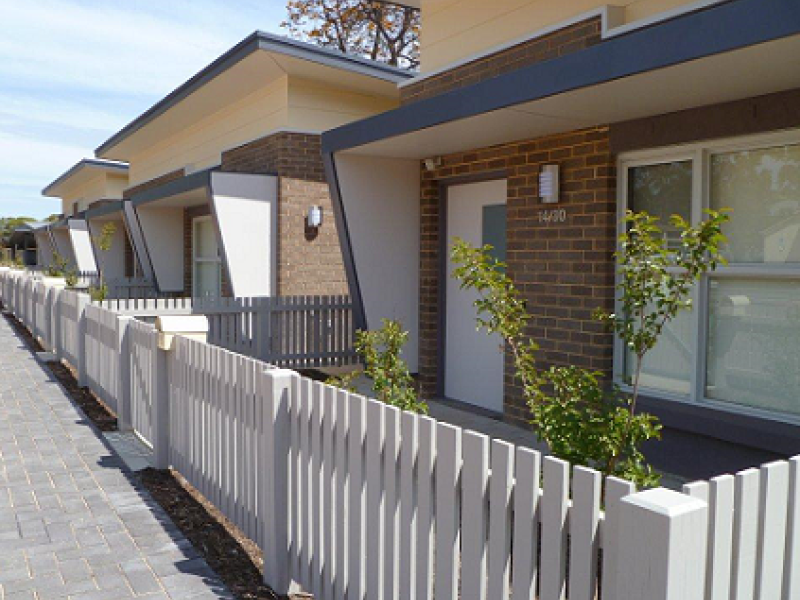 Front of homes surrounded by white picket fencing