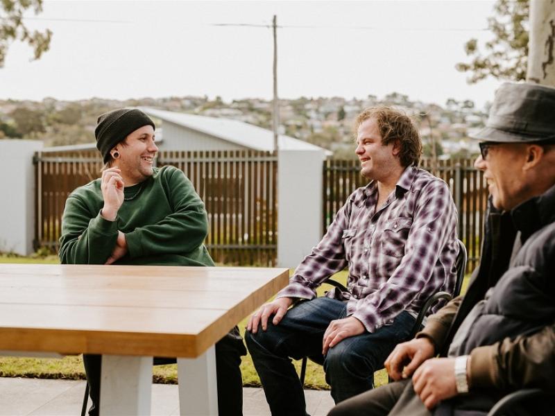 Three men chatting around a table.