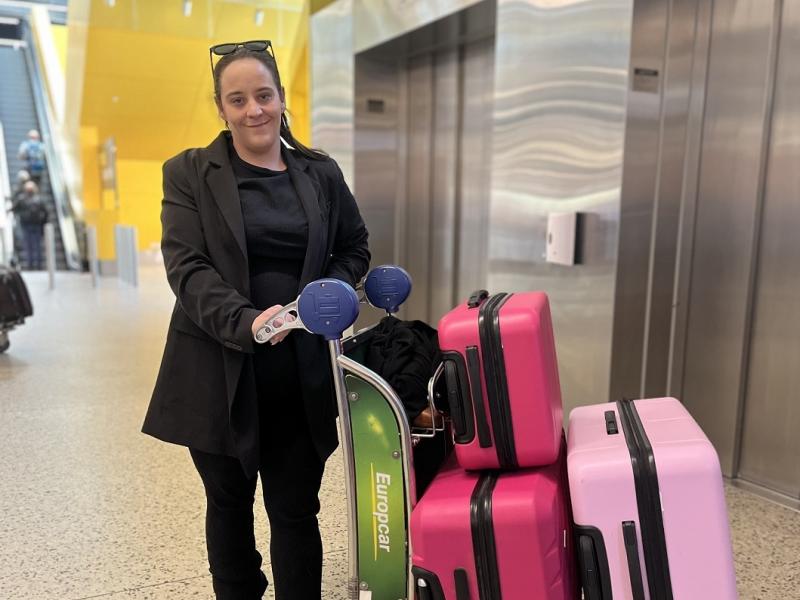 Woman standing with luggage cart outside a lift at the airport