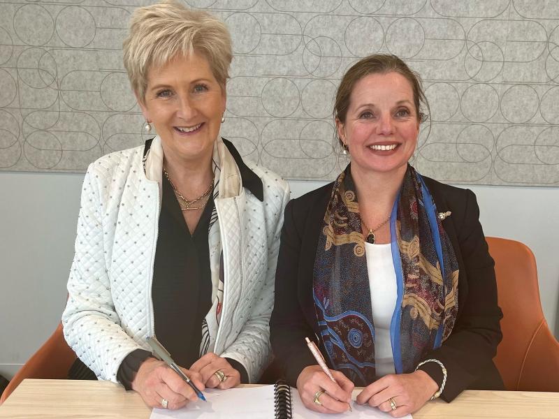 Two women sitting at a desk smiling at the camera