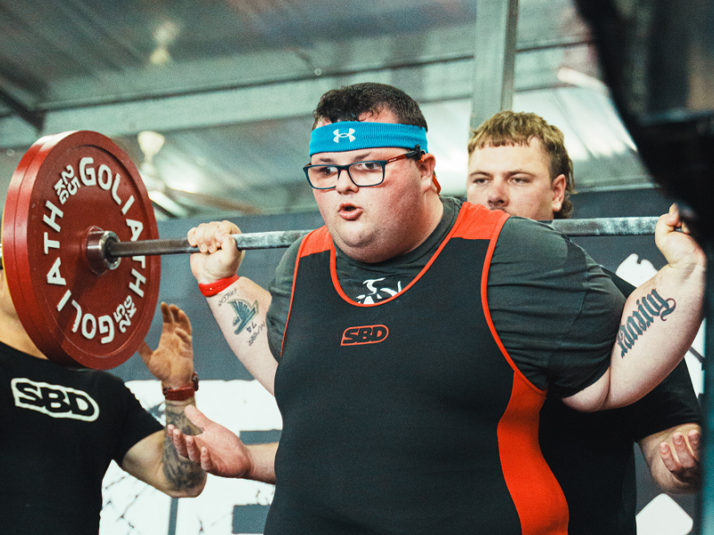 Man squatting weights at a gym