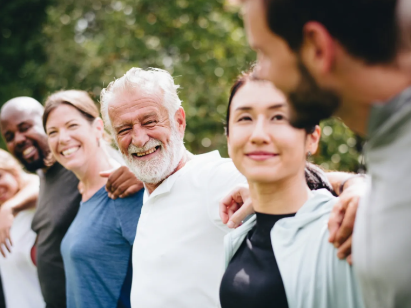 Six people smiling with arms around each others shoulders