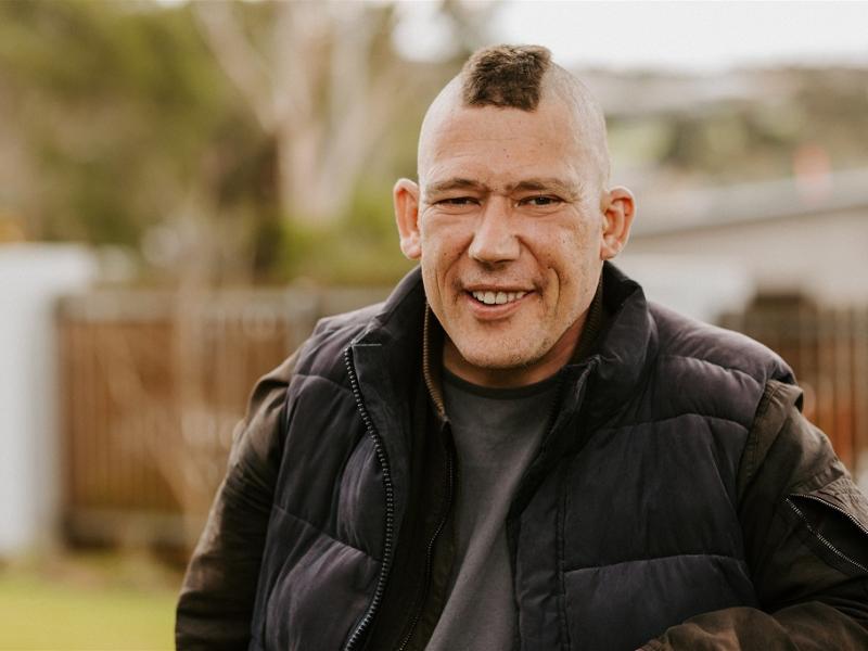 Man with short mohawk hairstyle smiling outside