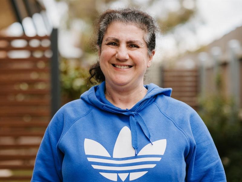 Woman smiling outside wearing a blue hooded jumper