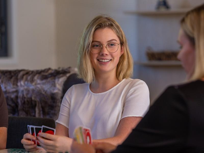 Young blonde female playing uno at a table