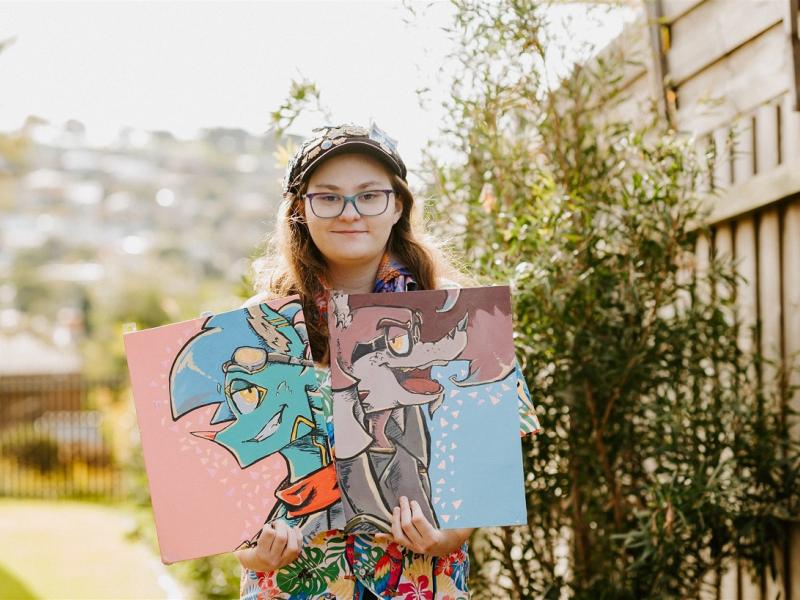 Woman standing outside holding two paintings