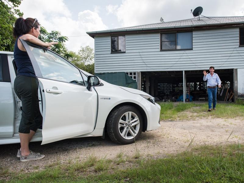 Man and woman standing outside a house near a car