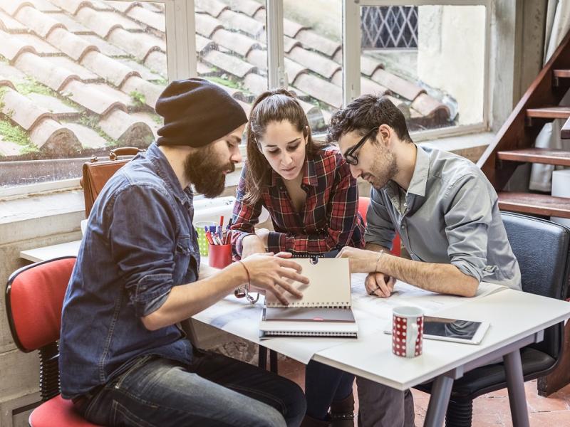 Two young men and a young woman looking at a planner diary