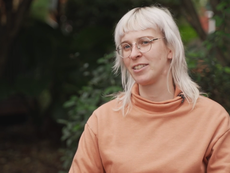 Woman with orange jumper outside talking