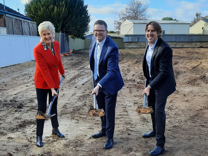 Three people digging dirt on a vacant plot