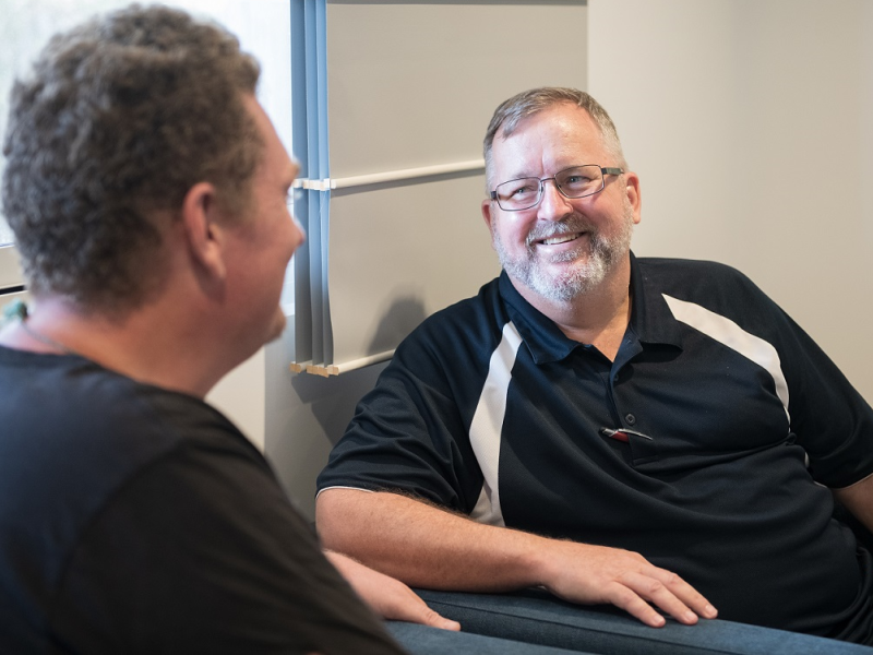 Two men comfortably chatting in a counselling room