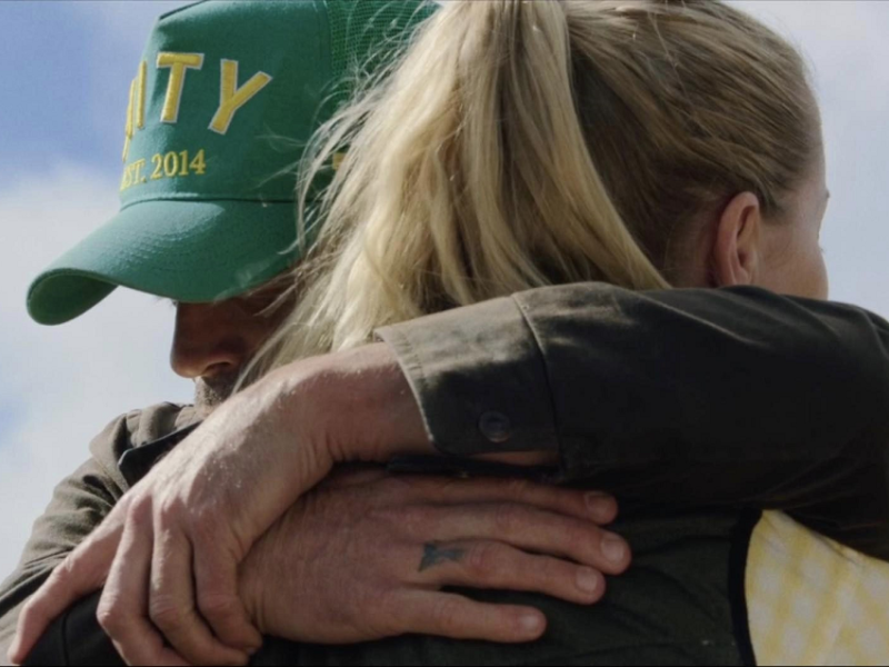 Man with a green baseball cap hugging a woman