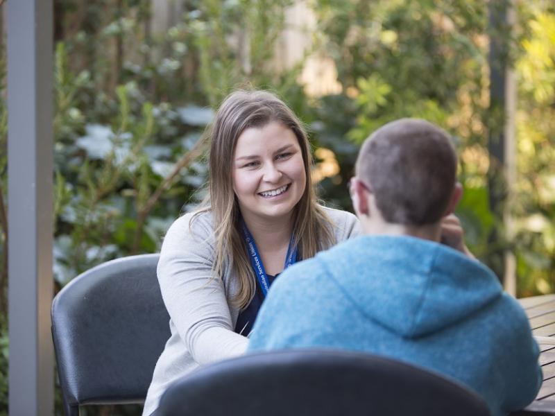 A support person talking to a man with a blue jacket