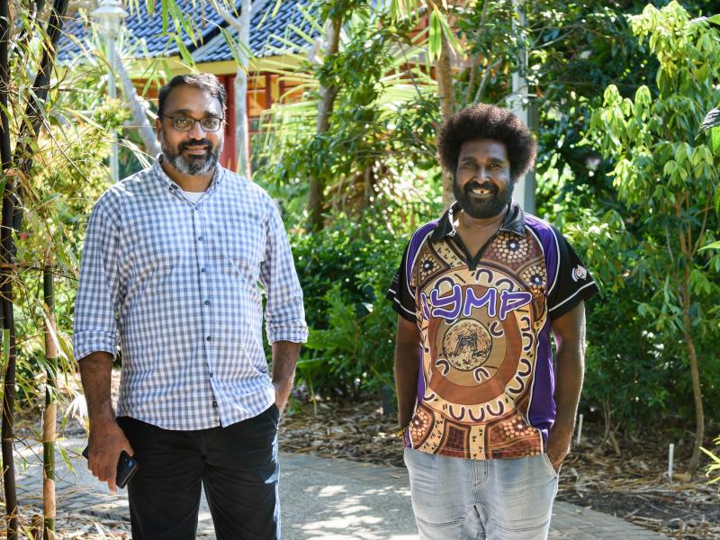 Two men of CALD background walking in the park smiling