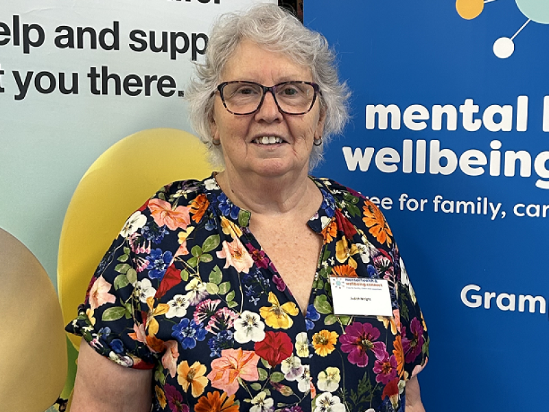 An older woman standing in front of a banner