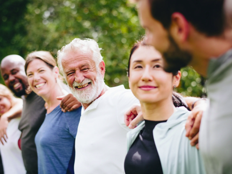 A multicultural line of people locked with arms around shoulders