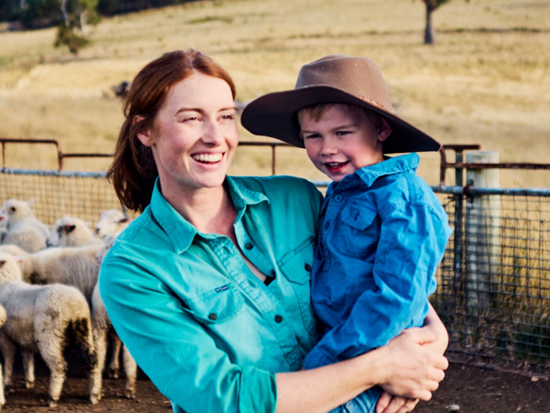 A woman holding a young boy on a farm