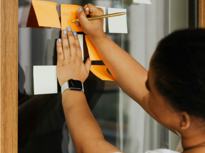 Person writing on Post it notes on a wall