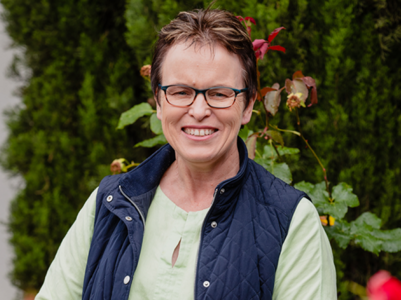 A woman smiling and standing in a garden