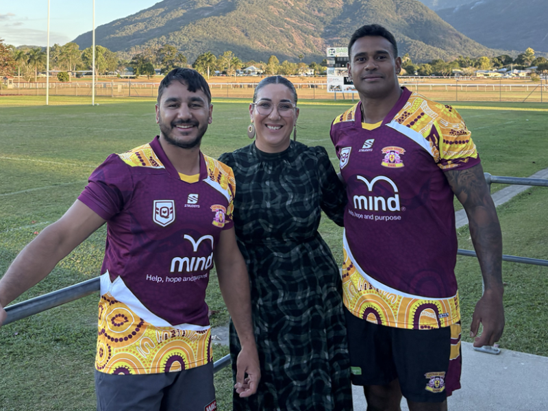 Two rugby players on each side of a woman