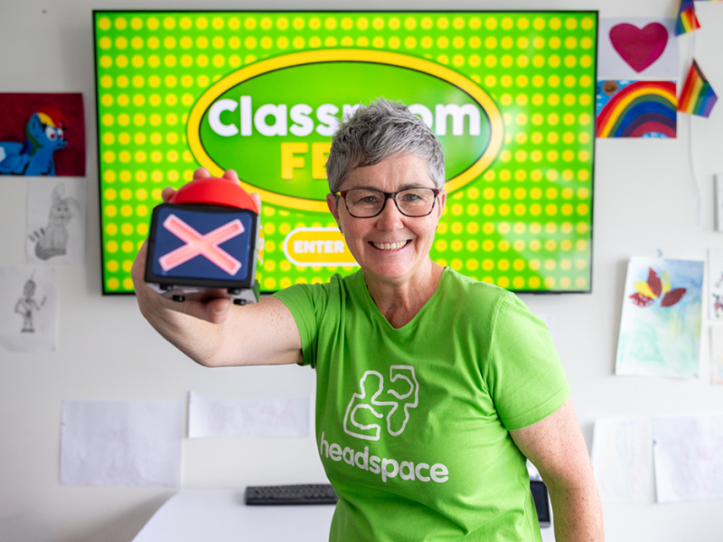 A person wearing a green headspace shirt holding and X