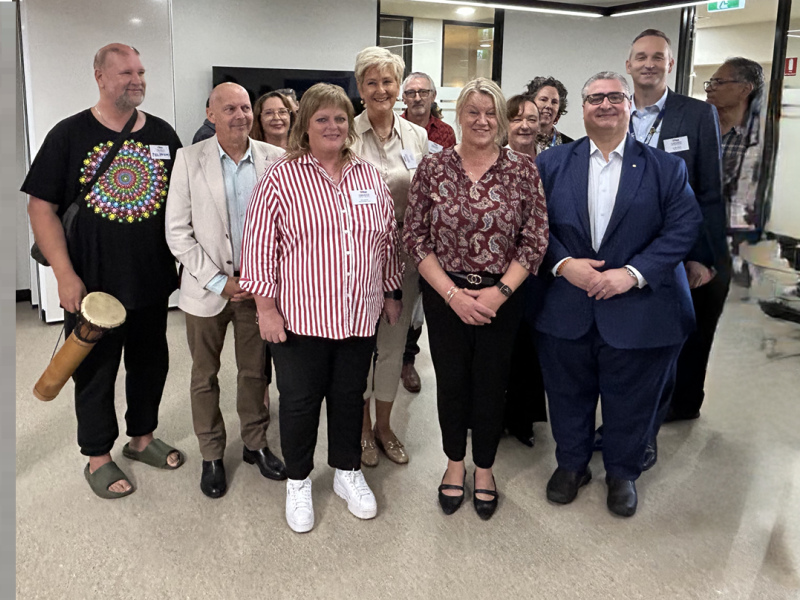 A group of 15 people standing and smiling