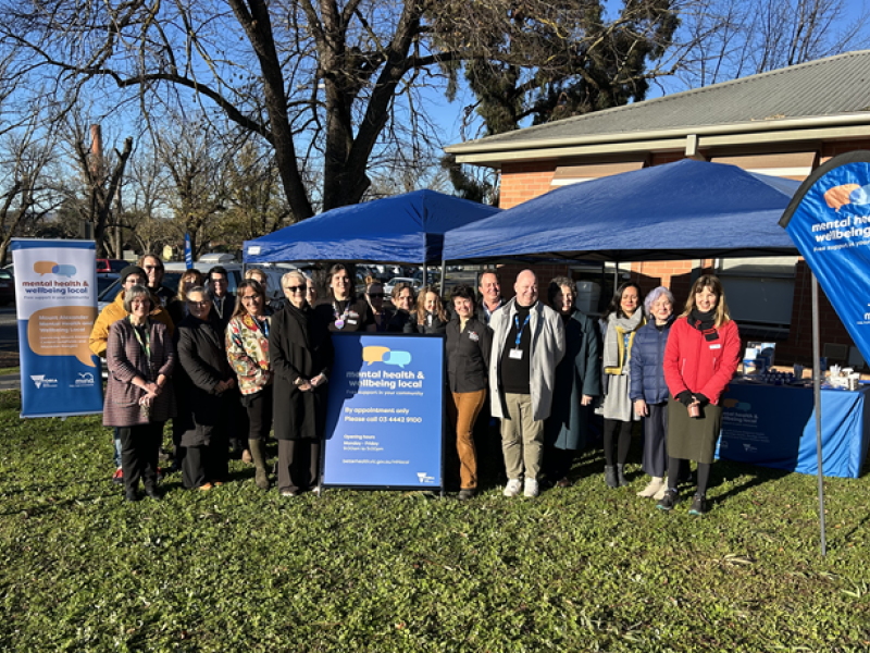 A group of 25 standing outside under a marquee and smiling