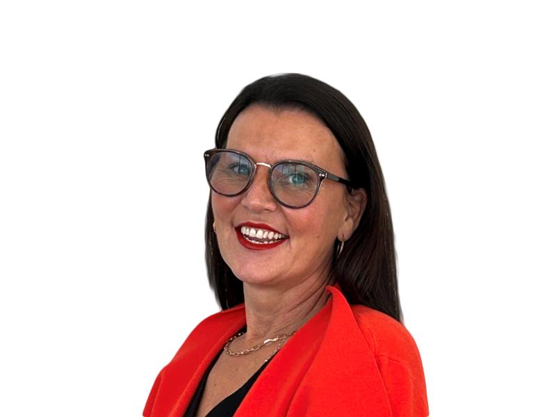 Smiling person with dark hair and glasses wearing a bright red blazer, photographed against a plain white background.
