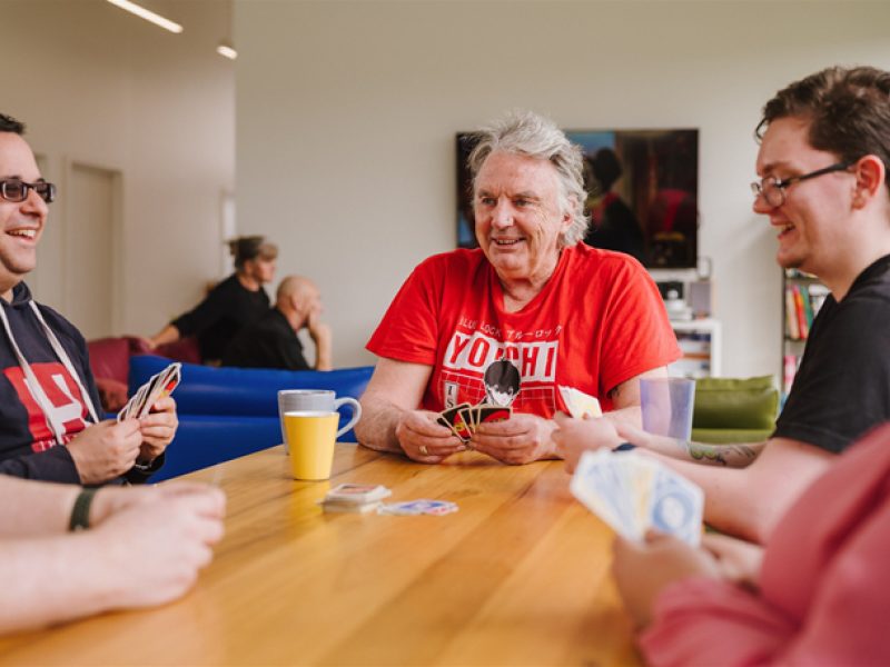 Three men playing UNO at a table and enjoying themselves