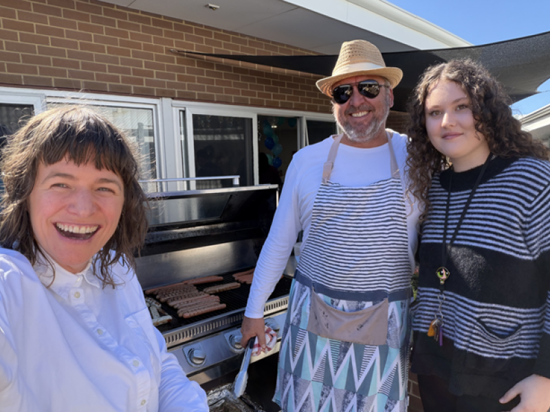 Three people enjoying a sausage sizzle