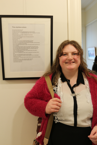 woman standing in front of a framed piece of writing