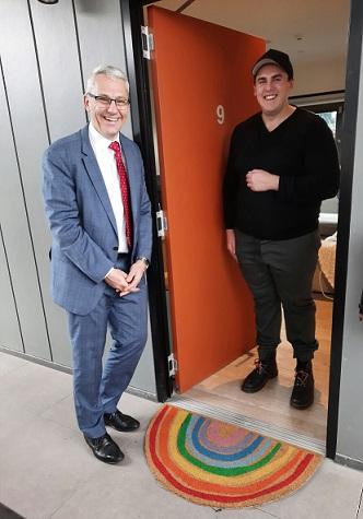 two men standing at the front entrance to an apartment