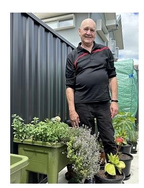 Man standing outside in garden with flowers