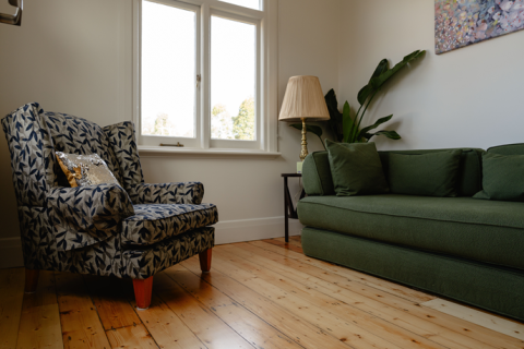A green sofa and white and blue chair in a lounge