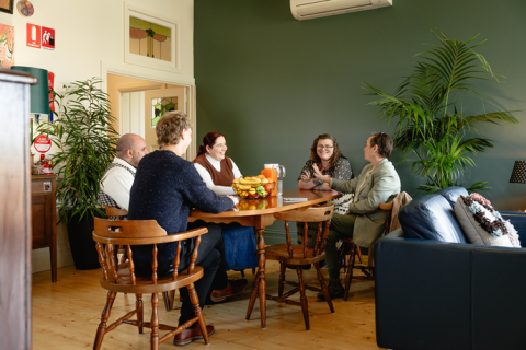 Five people enjoying themselves at a dinning room table